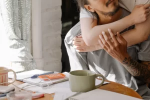 Close-up-of-man-being-hugged-from-behind-by-partner-at-home